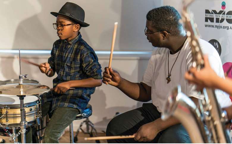  Ben Appiah coaches a young NYJO Academy drummer at a jazz jam